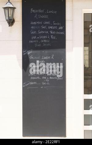 Menu board of cafe or restaurant. Whiteboard with text of menu in an European city. Caption - breakfast, lunch and dinner on signboard. Stock Photo