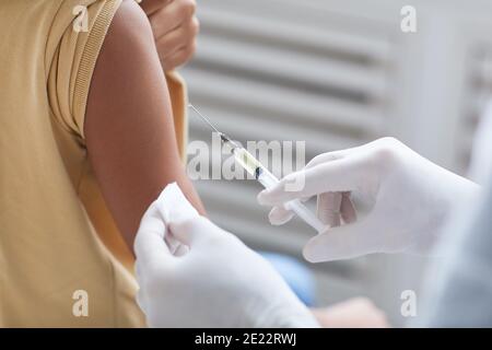 Close up of unrecognizable doctor vaccinating African-American boy, focus on hand holding syringe, copy space Stock Photo