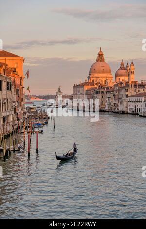 Sunset Grand Canal - A tourist gondola gliding over calm water at south end of the Grand Canal, on a quiet October evening. Venice, Veneto, Italy. Stock Photo