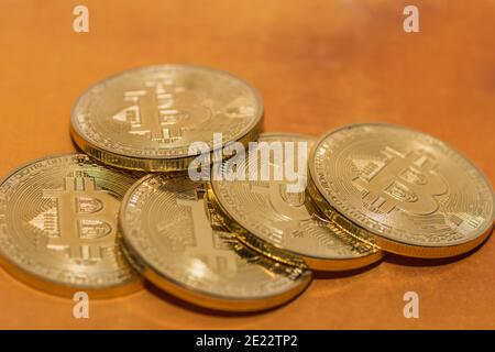 valuable bitcoins lie on top of each other on a golden background Stock Photo