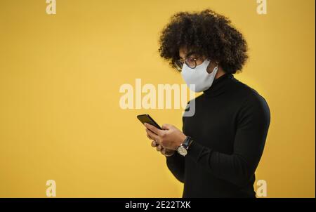 Portrait of mature man with smartphone in a studio on yellow background. Stock Photo