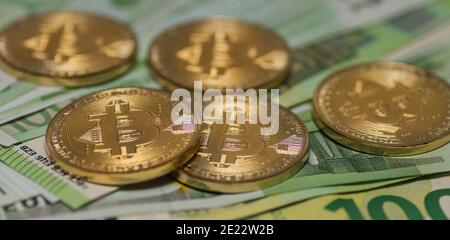 five golden bitcoins lying on many 100 euro bills panorama view Stock Photo