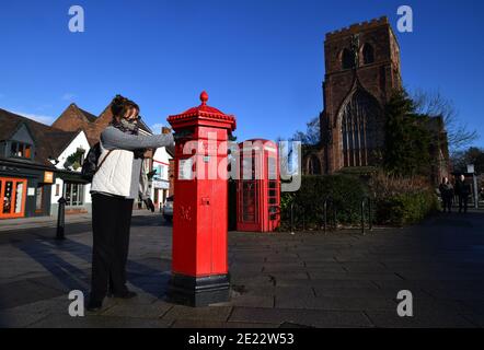 Woman posts a letter in a Victorian hexagonal shaped post box in Shrewsbury, Uk.  One of only 50 made they were designed by I.W. Penfold and made by C Stock Photo