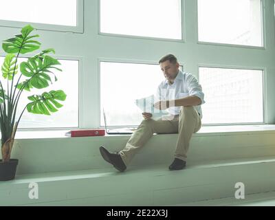 Male businessman works with documents while sitting by the window. Stock Photo