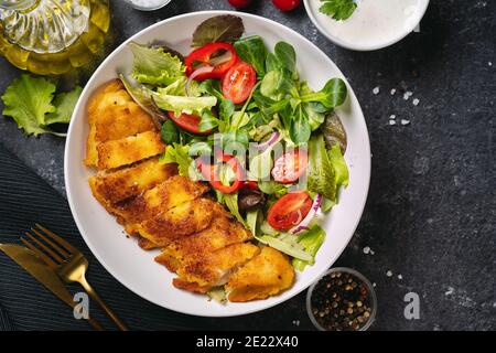 Close up of a plate with delicious breaded codfish with healthy salad Stock Photo