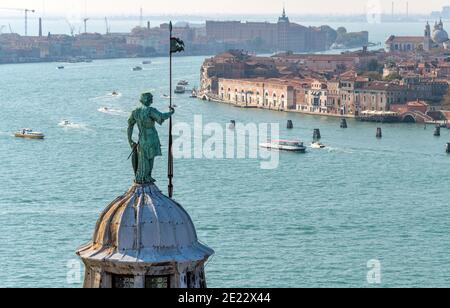 Guardian Angel - A bronze statue, standing at top of the dome of Basilica of San Giorgio Maggiore, watching over busy Giudecca Canal. Venice, Italy. Stock Photo