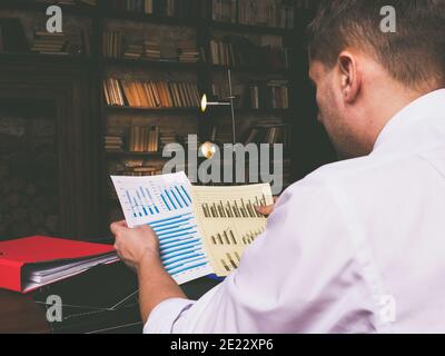 A businessman works late at night with documents and financial reports. Stock Photo