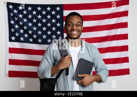 Smiling black man student standing over american flag Stock Photo