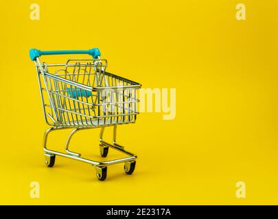 Empty shopping cart isolated on yellow background with copyspace. Retail store concept Stock Photo