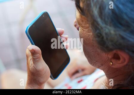 Adult brunette woman in casual clothing talking on the phone while resting at home. Housewife enjoying her free time. Blurred background. Stock Photo