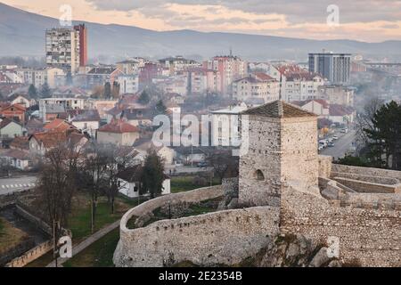 Beautiful soft colors of the clouds on a sunset sky above ancient fortress in front of a scenic, misty, dreamy cityscape of Pirot, Serbia Stock Photo