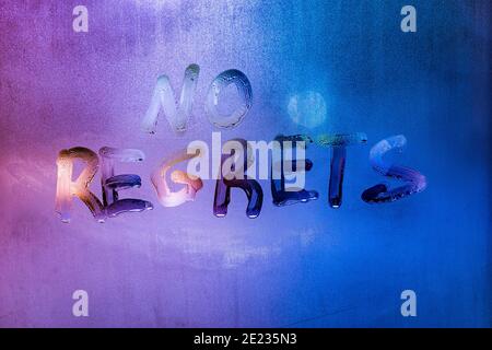 words no regrets hand written on purple-blue night foggy window glass Stock Photo