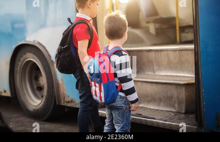 Two sweet boys with backpacks are entering a school bus. Stock Photo