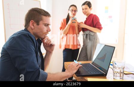 Two smiling female friends looking at man Stock Photo