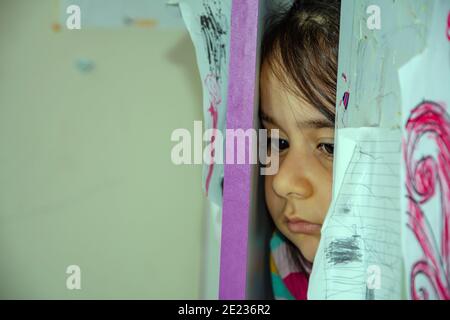 Little sad girl hiding in the wardrobe Stock Photo