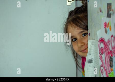 Smiling little girl hiding in the wardrobe Stock Photo