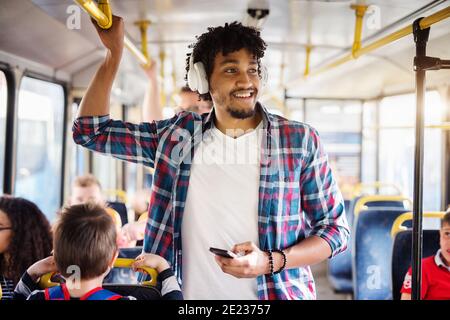 Young Afro-American man with headset on his head is looking away while riding in a bus. Stock Photo
