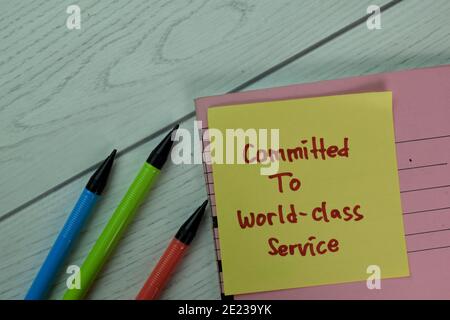 Committed To World-Class Service write on sticky notes isolated on Wooden Table. Stock Photo