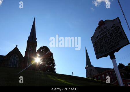 Sign marking site of Fort Cumberland store houses, Emmanuel Parish church (L) and First Presbyterian church (R) in background, Cumberland, Maryland MD Stock Photo