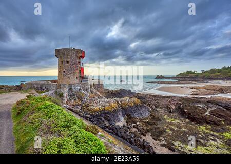 Image of Archirondel bay with a Napoleonic Jersey Tower with cloudy morning sky and low tide. Jersey Channel  Islands Stock Photo