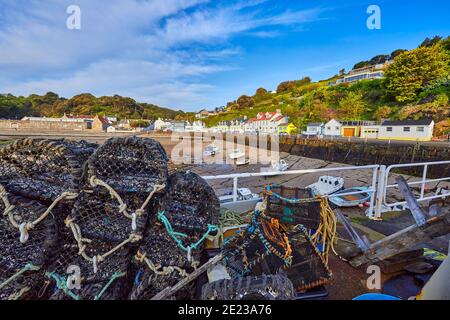 Image of the harbour at low tide at Rozel with small pleasure, fishing boats and lobster pots in the foreground. Rozel, St Martin, Jersey, Channel Isl Stock Photo
