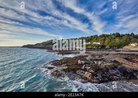 Image from the end of the harbour pier over rocks with the hedland at Rozel, St Martin, Jersey Channel Islands Stock Photo