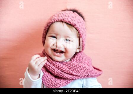Girl long hair dream pink background. Kid dreamy face wear knitted accessory. Kid girl wear cute knitted fashionable hat and scarf accessory. Stock Photo