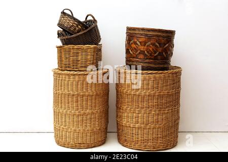 Two stacks of handmade natural wicker straw baskets for home storage of kids toys and small goods at white interior Stock Photo