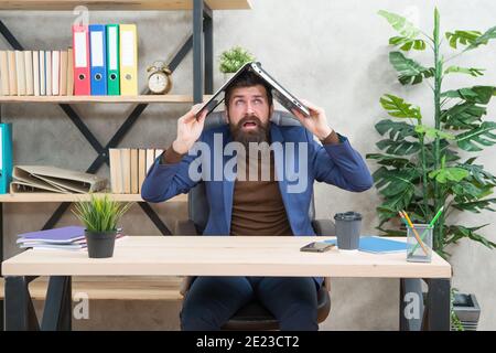 Crazy trader in formalwear hold notebook computer on head sitting at desk in business office, e-commerce. Stock Photo