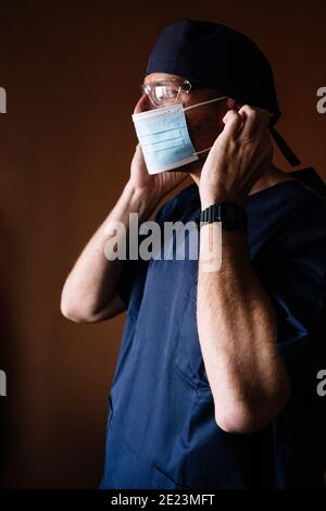 Hispanic male doctor putting on face mask. Stock Photo