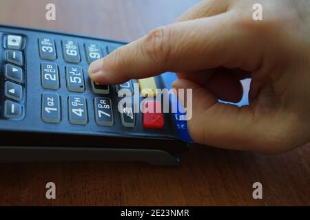 Closeup shot of a male's hand entering pin code for a credit card on POS terminal Stock Photo