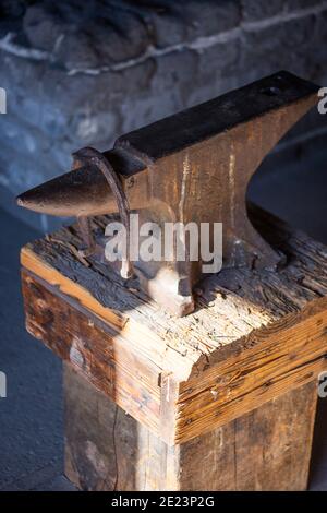 Old rusty anvil tool on a wooden surface Stock Photo
