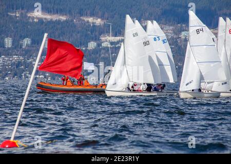 FJ sailboats line up on the start line of a collegiate sailing regatta in English Bay, Vancouver, British-Columbia between a committee boat and the pi Stock Photo