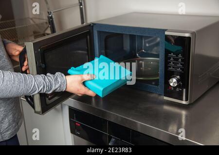 A women puts a food-grade silicone bag into a microwave as part of a zero-waste lifestyle to replace plastic bags Stock Photo