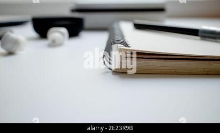Notepad for notes on the rings and a black felt-tip pen. Workplace in the office. Mobile phone with headphones. Business ideas and creativity. Stock Photo