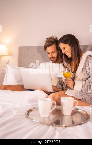 Happy loving couple relaxing in the bedroom and using laptop Stock Photo