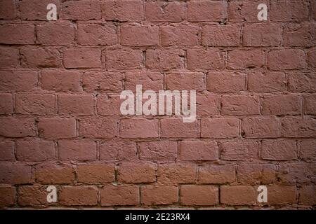Old brick wall of a building, red, under the paint. Textured background. Stock Photo