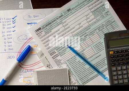 A simple versatile US federal income tax return concept image with an empty 1040 form on wooden table together with notes, calculations, pen, marker, Stock Photo
