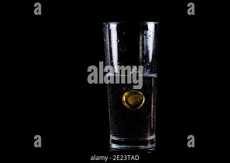 Clarksburg, MD, USA 01-05-2021: A close up image of a metal Stella Artois beer bottle cap thrown into a half full tall glass of water with splashes an Stock Photo