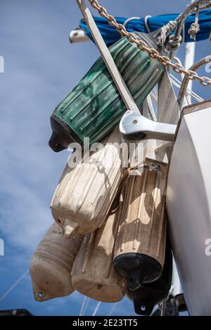 Boat fenders hang in a bunch stored off the stern of a cruising sailboat. Stock Photo