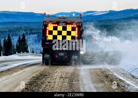 A rear view of a Department of Highways snow plow truck plowing snow from the road surface in rural Alberta Canada. Stock Photo