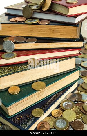 Pile of books surrounded by many different coins Stock Photo
