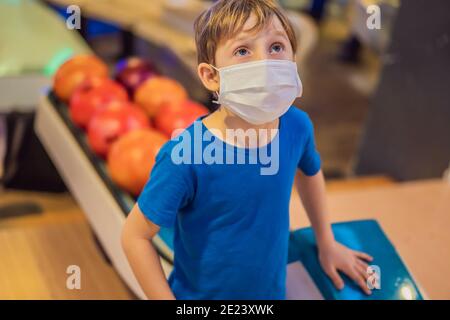 Boy playing bowling with medical masks during COVID-19 coronavirus in bowling club Stock Photo