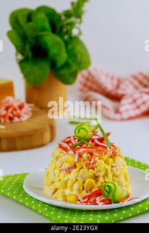 Crab meat salad with sweet corn, cheese and eggs decorated with corn chips and cucumber. Vertical photo. Stock Photo