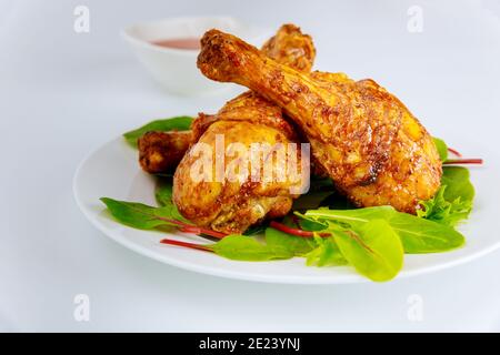 Roasted turkey drumsticks with salad on white background, Close up. Stock Photo
