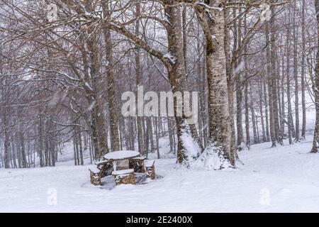 Beautiful shot of a snowy picnic area with a bench on Gipuzkoa's mount Aizkorri Stock Photo