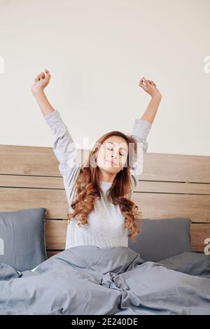 Asian woman stretching in bed Stock Photo
