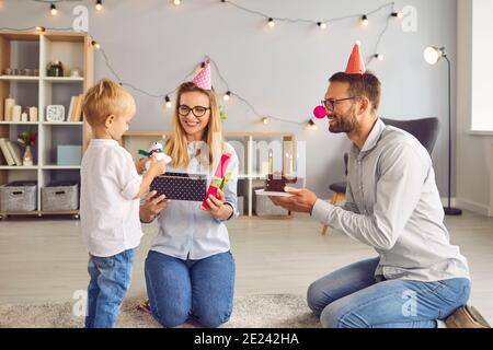 Happy mom and dad looking at their little son studying his new toy he got as birthday present Stock Photo