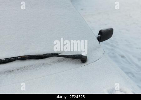 Selective focus of car windscreen covered with snow in cloudy winter weather Stock Photo