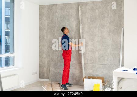 Rear back behind view photo of unrecognizable repairman master using rule to measure the required width of drywall and put label mark Stock Photo